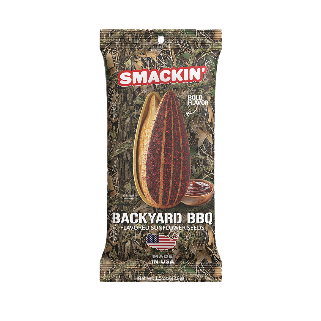 A Smackin' Backyard BBQ flavored sunflower seeds bag featuring a camouflage design, an enlarged red seasoned sunflower seed, a small wooden bowl of dark barbecue sauce, and an American flag shaped like the USA