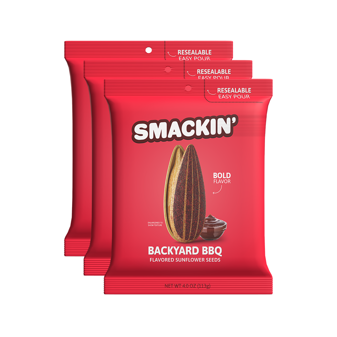 Digital product photography of three bright red Smackin' Backyard BBQ flavored sunflower seed bags on a white background featuring a large striped sunflower seed and a bowl of BBQ sauce with Resealable Easy Pour tops