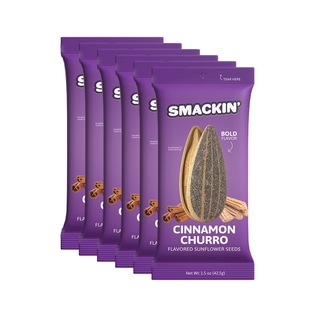 Digital product photography of a stack of five purple Smakin' Cinnamon Churro flavored sunflower seed bags against a clean white background prominently displaying an enlarged sunflower seed, cinnamon sticks, and churros on the label with bold BOLD FLAVOR text