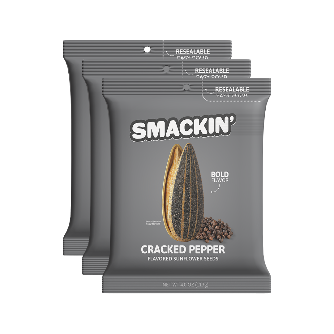 Product photography of three dark gray Smakin' Cracked Pepper Flavored Sunflower Seeds bags featuring the brand logo an enlarged sunflower seed with black peppercorns and visible resealable easy pour tops