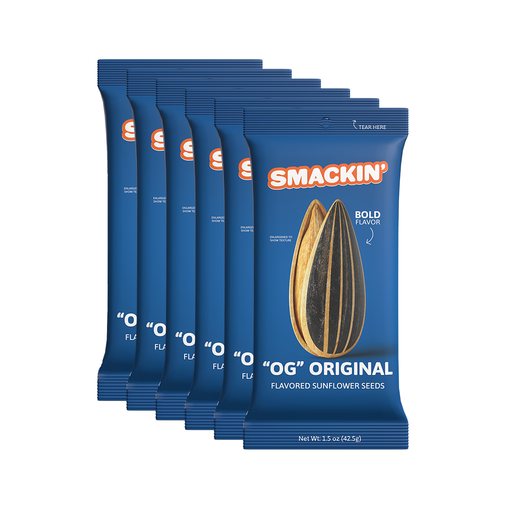 Six dark blue Smackin' 'OG' Original flavored sunflower seed pouches stacked, each prominently displaying an orange logo and two large striped sunflower seeds with 'BOLD FLAVOR' text