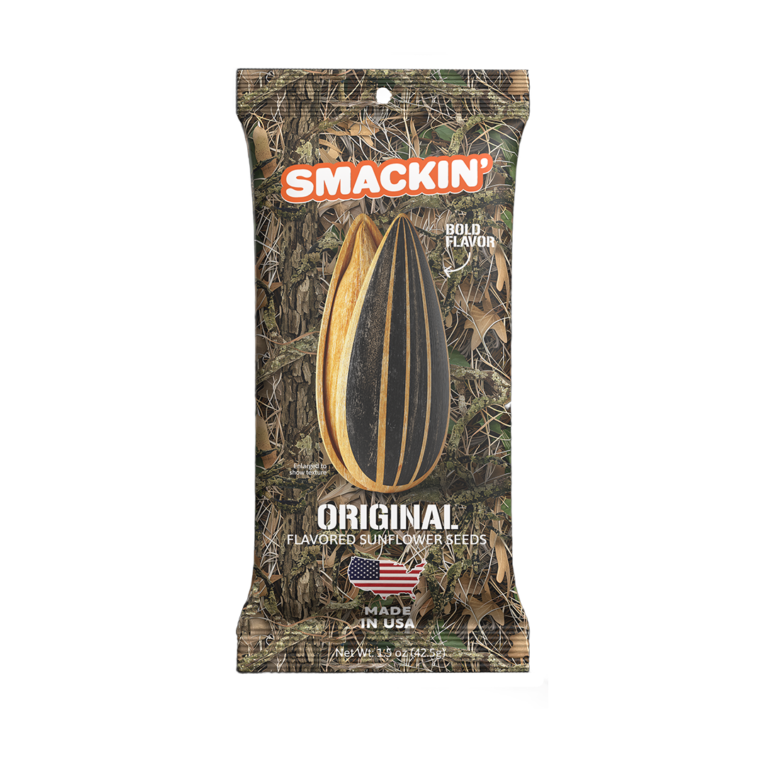 Product photo of a Smackin' Original Flavored Sunflower Seeds package featuring a camouflage design, a prominent black and white striped sunflower seed graphic, orange Smackin' branding, and a "Made in USA" American flag logo