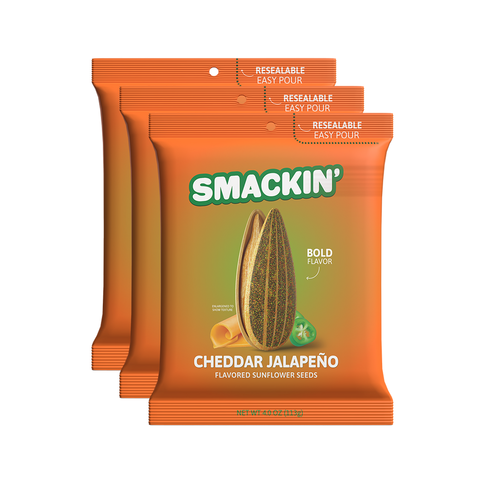 Product packaging featuring three bright orange Smackin' Cheddar Jalapeño Flavored Sunflower Seeds bags each with a green logo a large sunflower seed bold flavor text a yellow cheddar curl and a green jalapeño slice and "Resealable Easy Pour" printed at the top