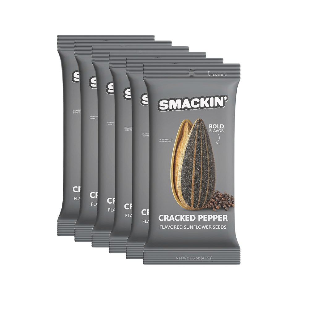Six gray Smackin' Cracked Pepper flavored sunflower seed bags stacked diagonally feature a large striped seed, scattered peppercorns, and a "Bold Flavor" text