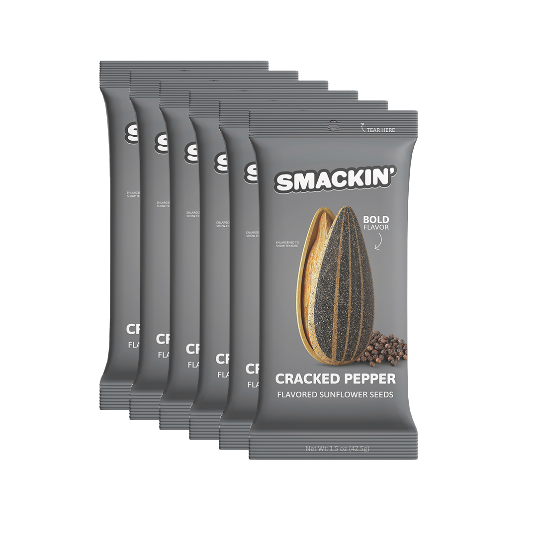 Six gray Smackin' Cracked Pepper flavored sunflower seed bags stacked diagonally feature a large striped seed, scattered peppercorns, and a "Bold Flavor" text