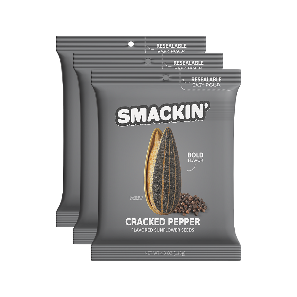 Product photography of three dark gray Smakin' Cracked Pepper Flavored Sunflower Seeds bags featuring the brand logo an enlarged sunflower seed with black peppercorns and visible resealable easy pour tops